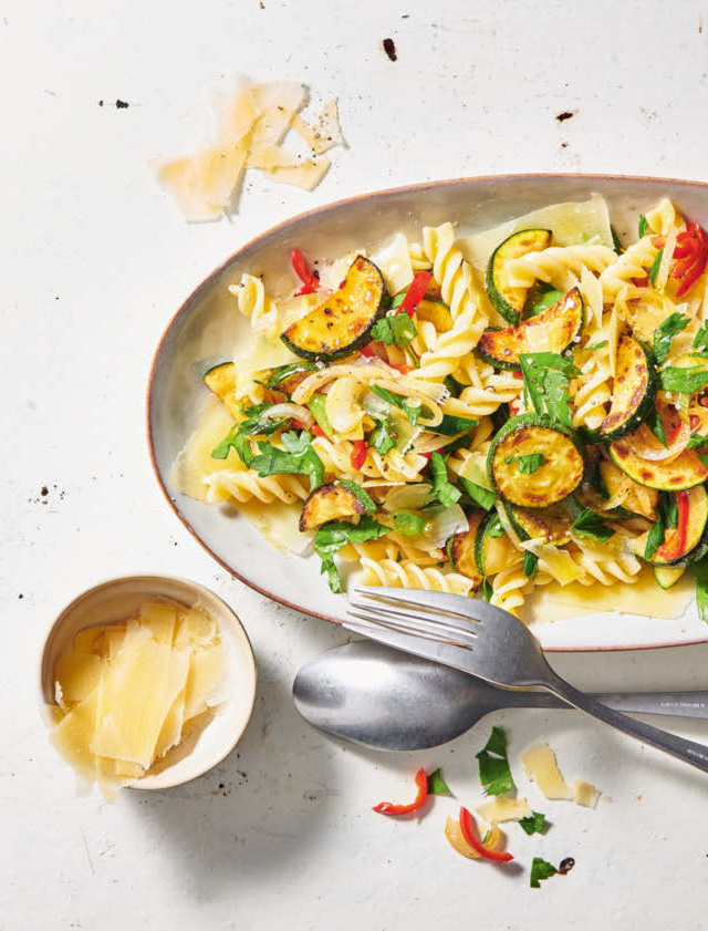 [Translate to Französisch:] Ein Teller mit Fusilli, goldbraun gebratenen Zucchetti, Chili, frischen Kräutern und gehobeltem Parmesan