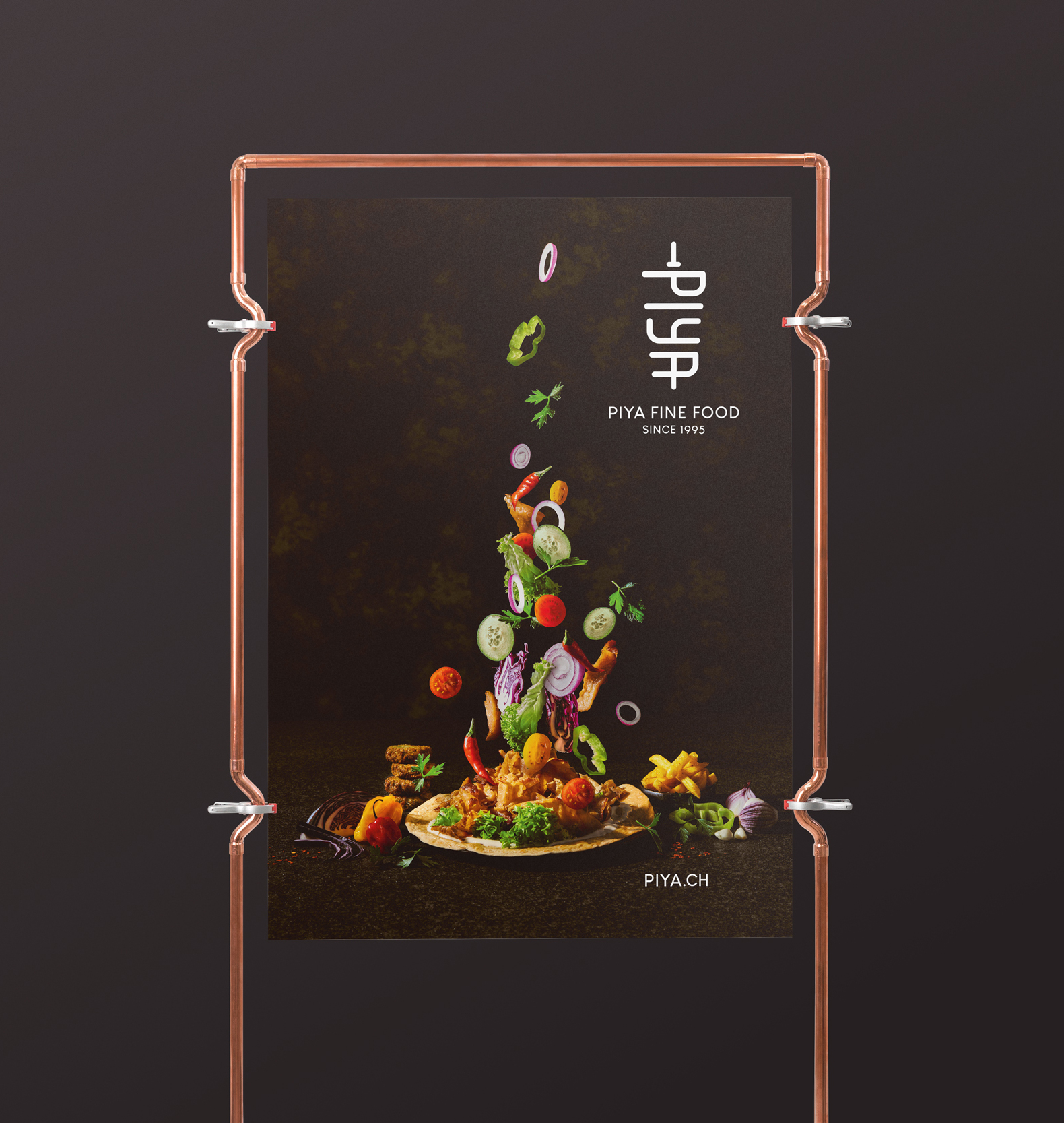 Eine PIYA-Werbekarte: Ein Haufen buntes gerüstetes Gemüse schwebt über einem Teller und bildet einen Kontrast zum dunklen Hintergrund.