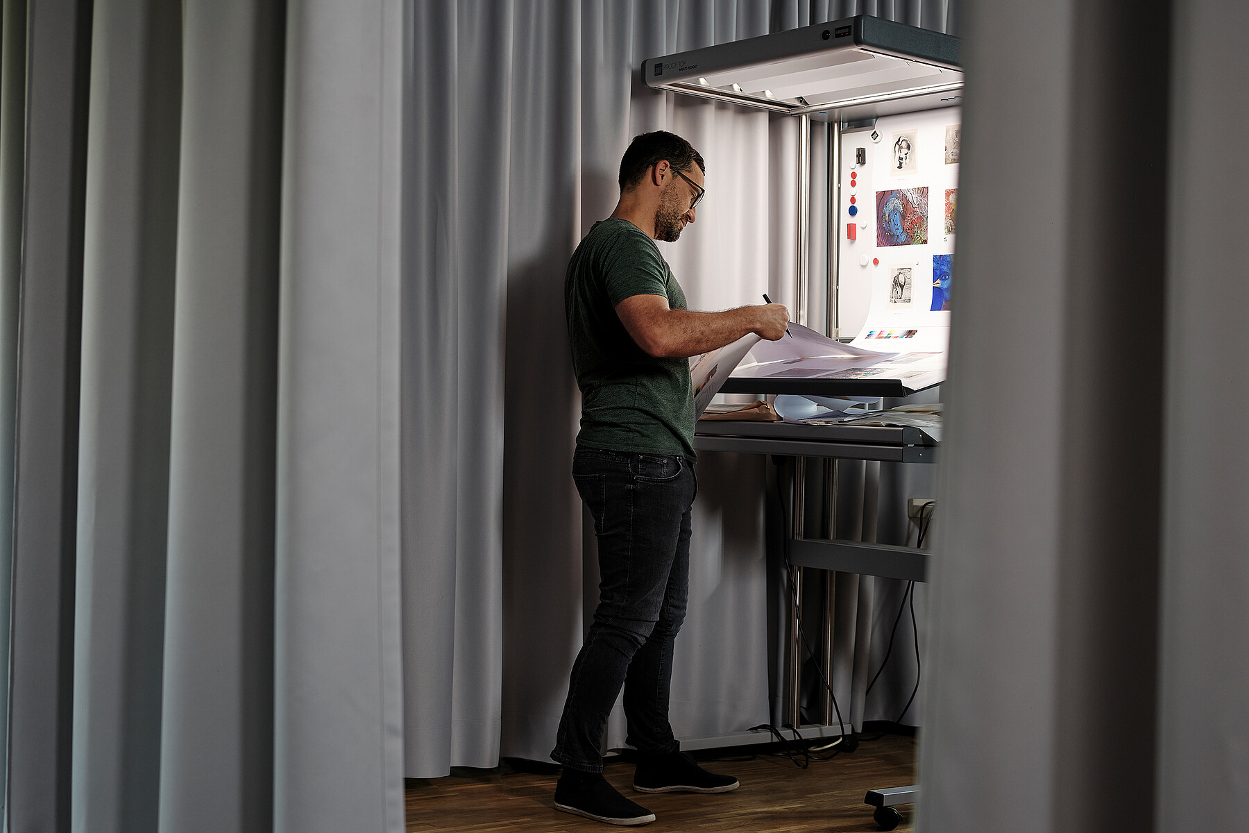 Ein Mitarbeiter der Bildbearbeitung begutachtet die Druckresultate.