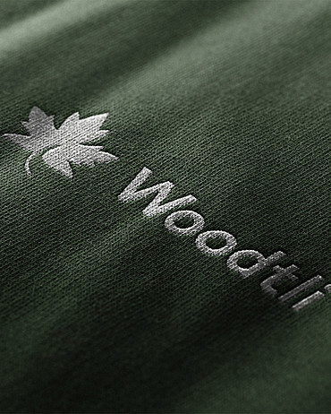 Das neue Woodtli-Logo enthält ein Ahornblatt. Hier erscheint es in Weiss auf blassgrünem Stoff.