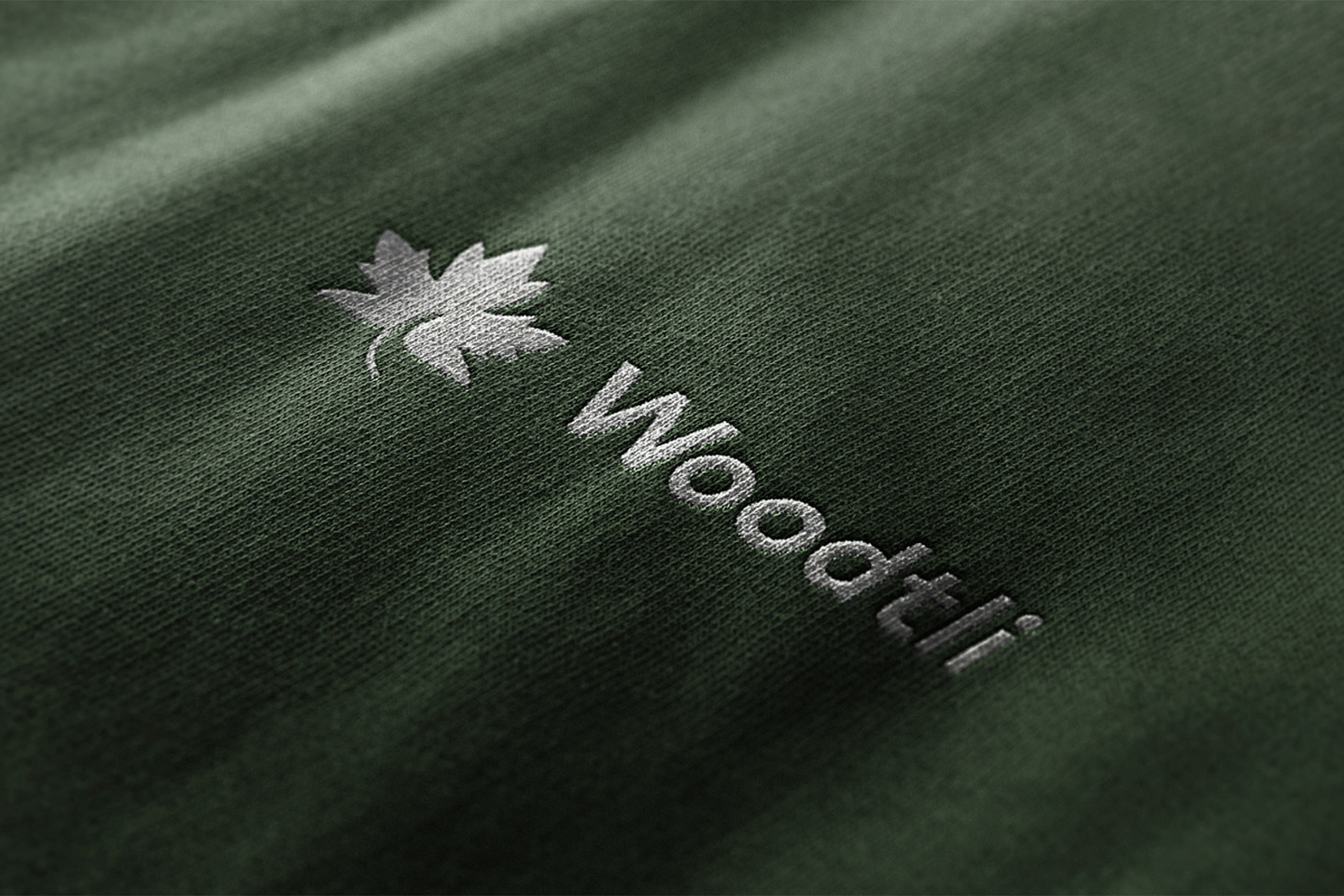 Das neue Woodtli-Logo enthält ein Ahornblatt. Hier erscheint es in Weiss auf blassgrünem Stoff.