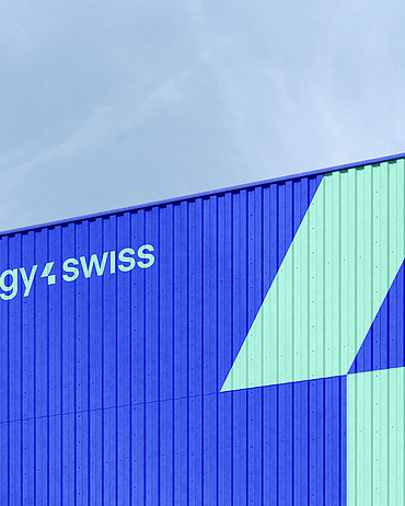 Das neue energy4swiss-Logo und eine übergrosse Version des Markenzeichens in Türkis auf einem blauen Container 