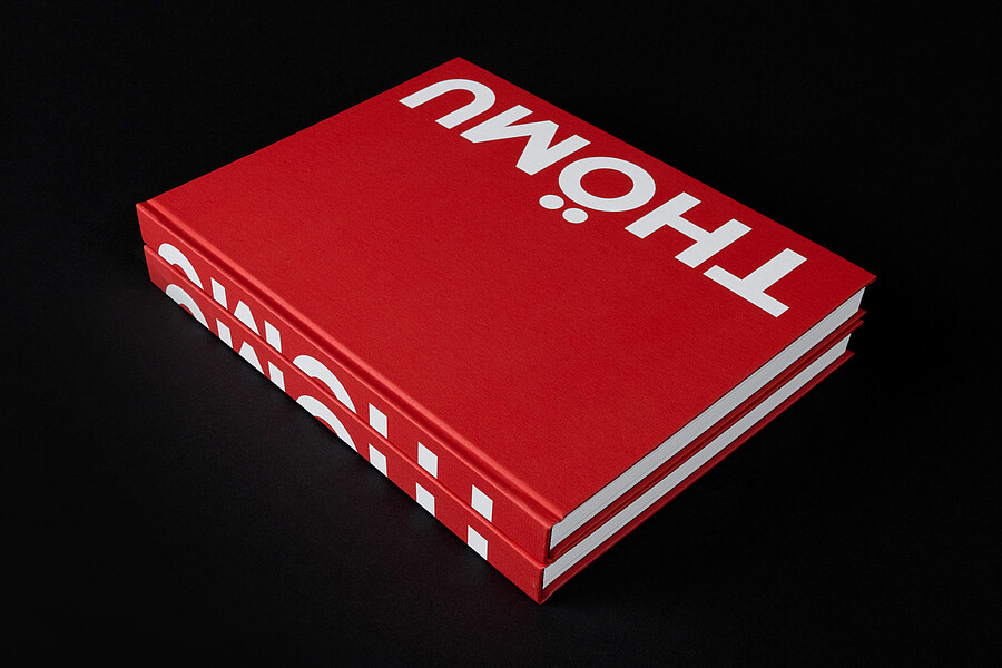 Zwei übereinanderliegende Exemplare des knallroten Buches über den Thömus-Gründer mit dem Titel «Thömu» 