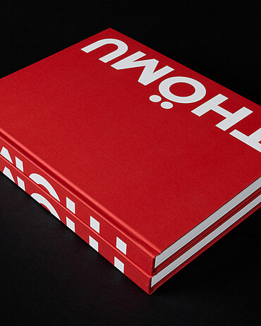 Zwei übereinanderliegende Exemplare des knallroten Buches über den Thömus-Gründer mit dem Titel «Thömu» 
