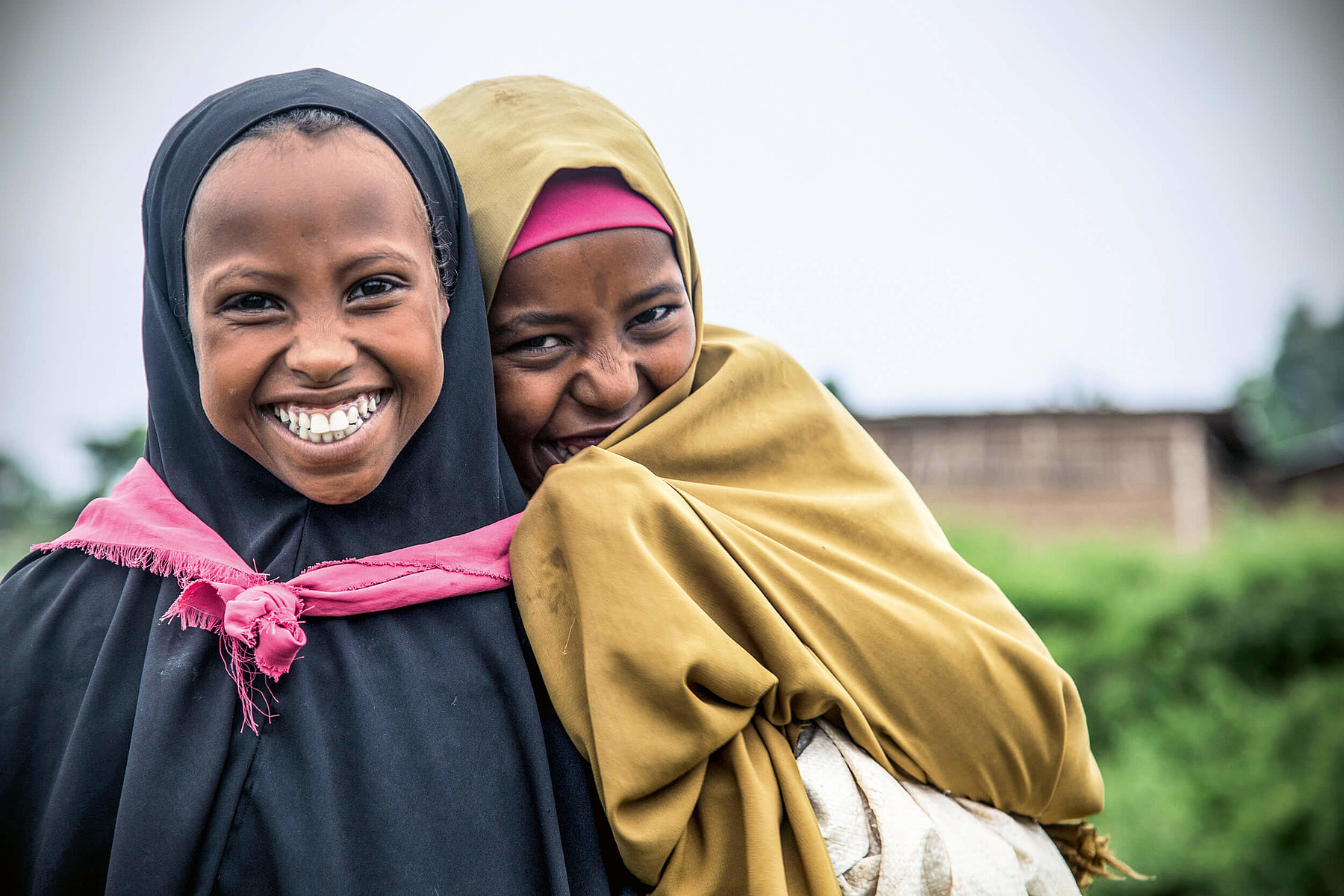 Zwei fröhliche afrikanische Mädchen mit Kopftüchern