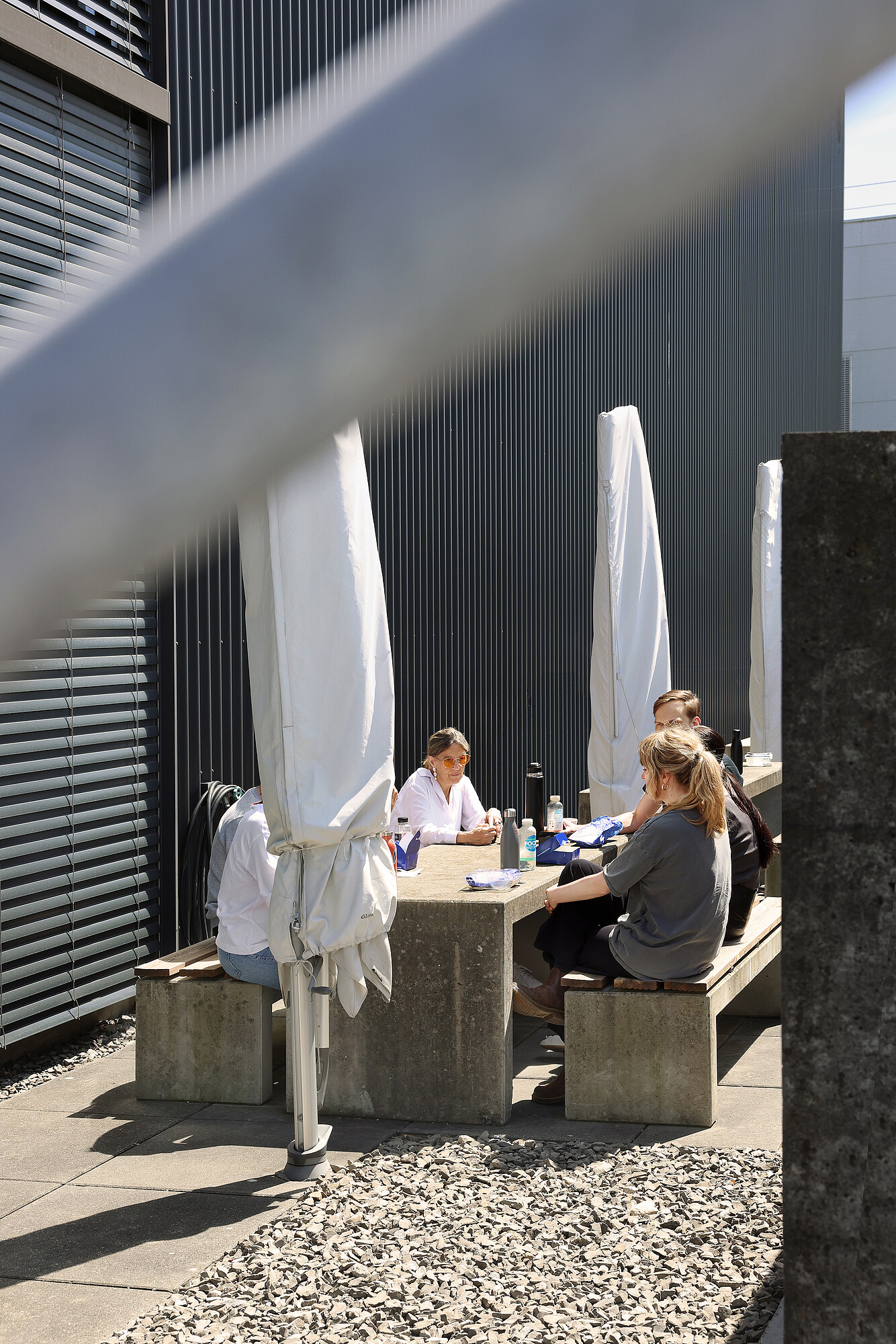 Quelques collaborateurs sont assis ensemble à une table au soleil.