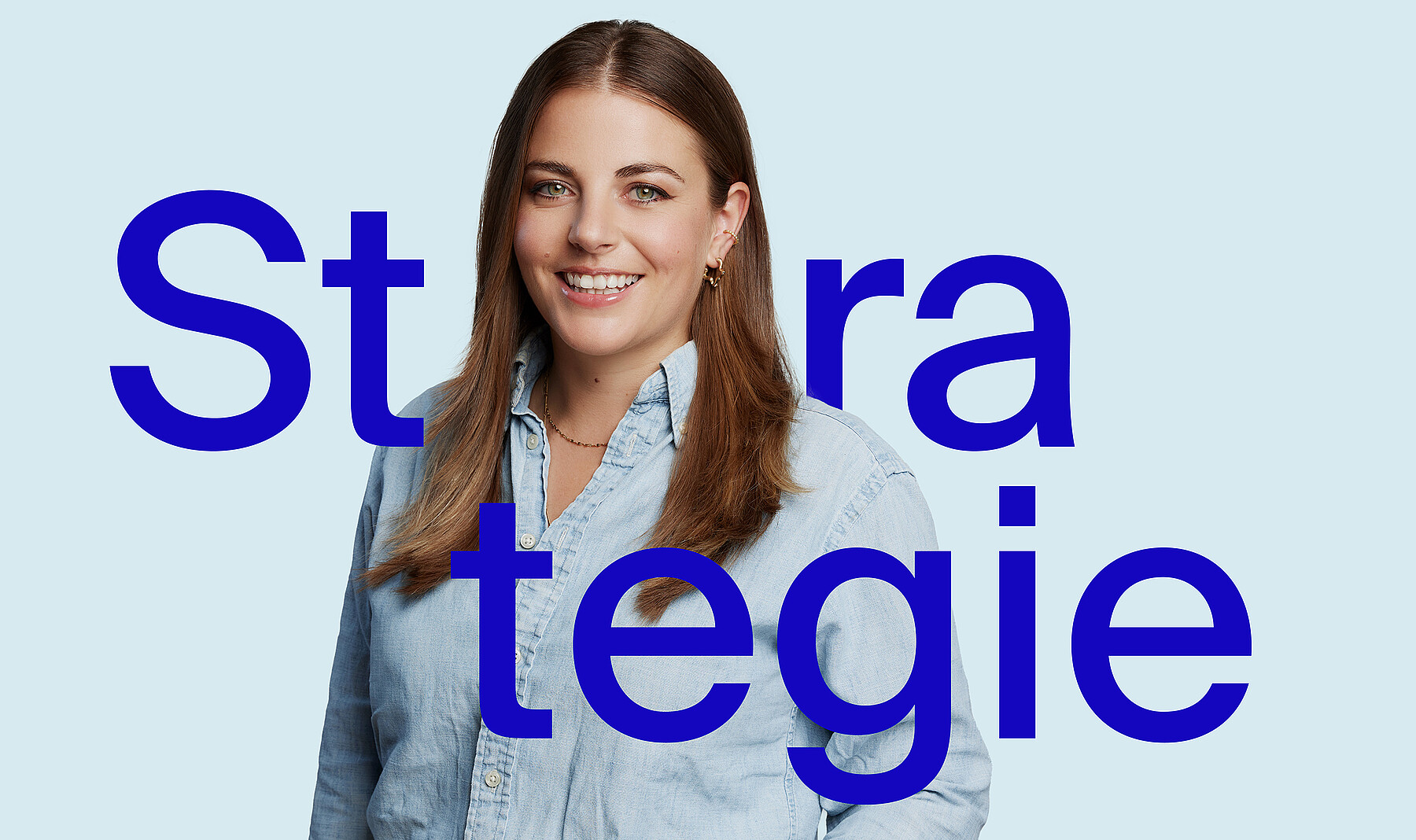 Junge Frau mit freundlichem, offenem Lächeln, langen braunen Haaren und heller langärmliger Bluse. Bei ihr steht in grossen blauen Buchstaben das Wort Strategie.