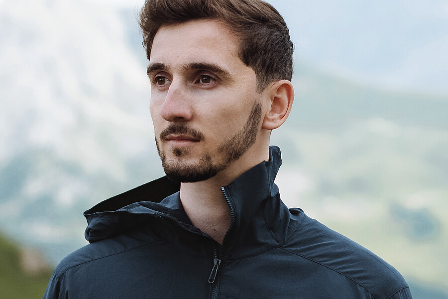 Ein Mann in den Bergen trägt eine sportliche Jacke mit dem Label #DiniWält der Jungfrau-Region.